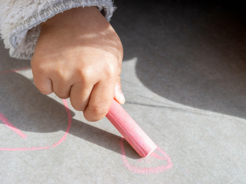 Ein Kind malt mit Straßenkreide