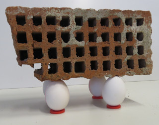 Vier Eier tragen einen Ziegelstein.